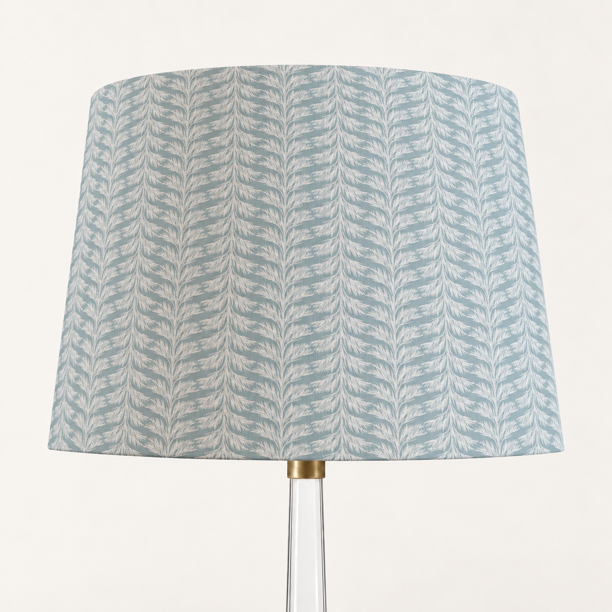 Sky blue Sabal Stripe tapered drum lampshade on a clear glass lamp